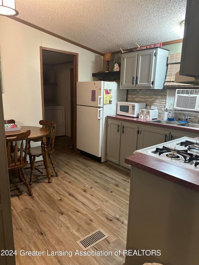 kitchen featuring white appliances, a textured ceiling, gray cabinets, light hardwood / wood-style floors, and washer / dryer