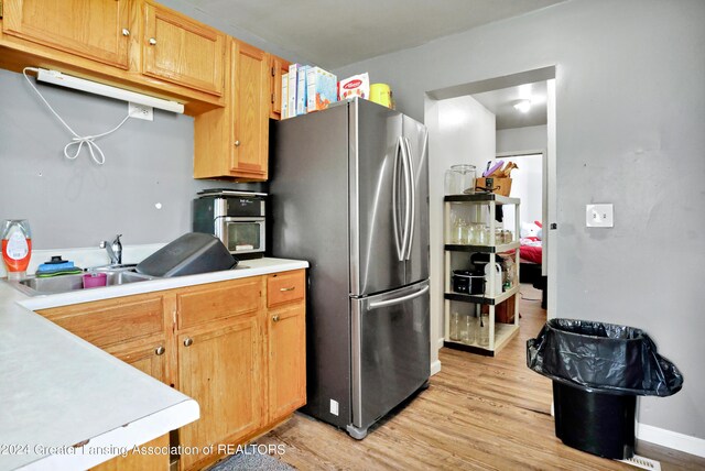 kitchen with sink, light wood-type flooring, and stainless steel fridge