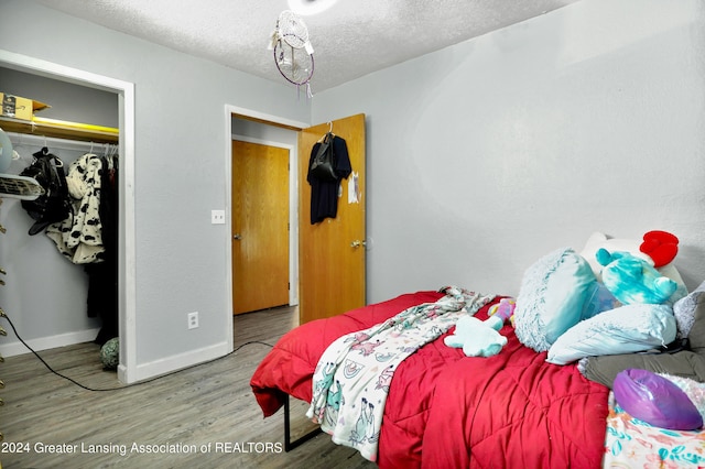 bedroom with a textured ceiling, a closet, and wood-type flooring