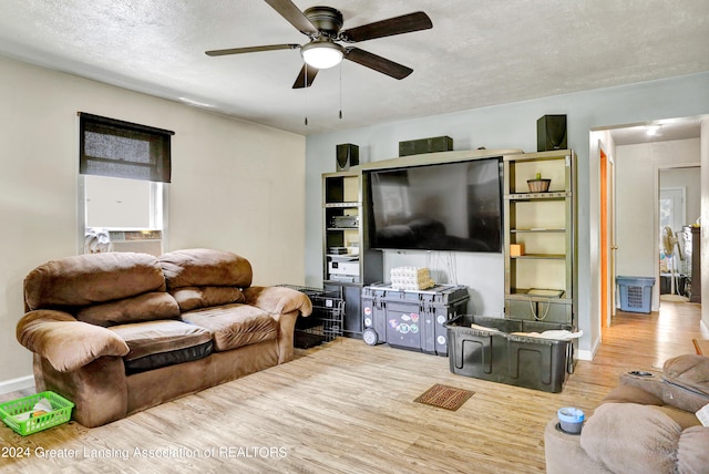 living room with a textured ceiling, ceiling fan, and light wood-type flooring