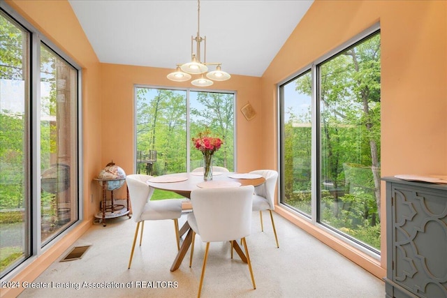 dining room featuring a notable chandelier, a wealth of natural light, and vaulted ceiling