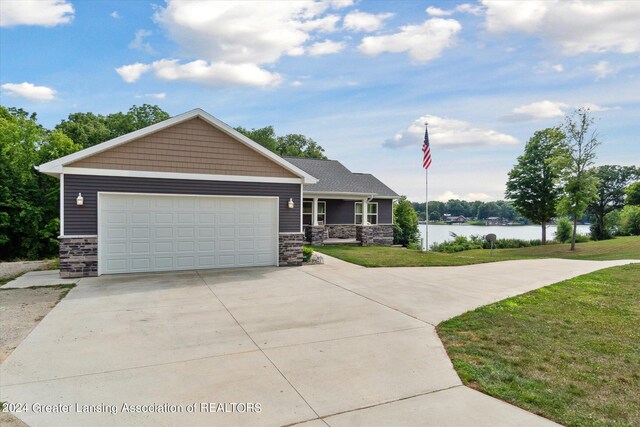 view of front facade featuring a garage, a water view, and a front lawn