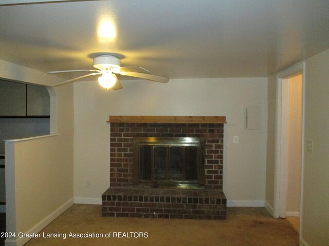 unfurnished living room with ceiling fan, a brick fireplace, and carpet flooring