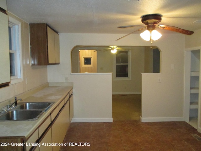 kitchen featuring sink, a textured ceiling, ceiling fan, and dark tile patterned flooring