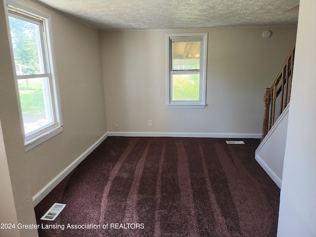 empty room with carpet and a textured ceiling