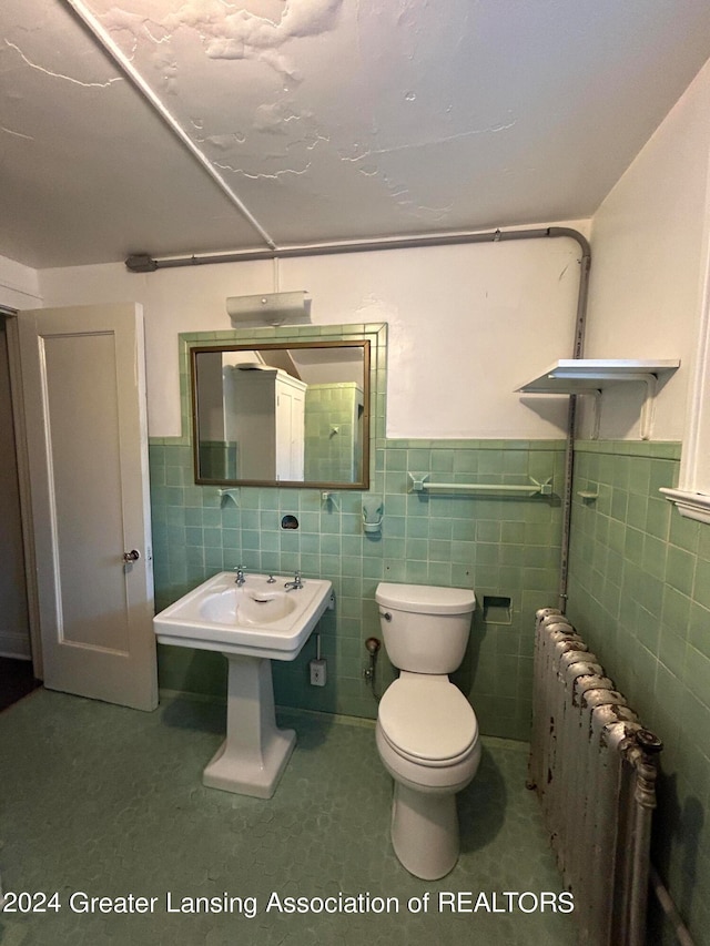 bathroom with tile patterned floors, toilet, radiator, and tile walls