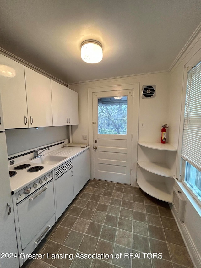 kitchen featuring sink, white cabinetry, crown molding, and dark tile patterned flooring