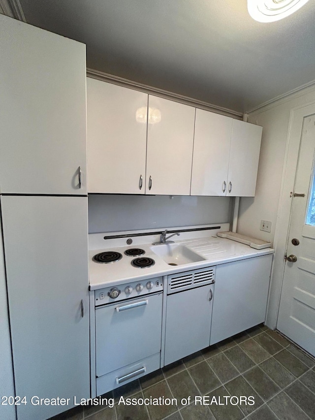 kitchen with sink, dark tile patterned floors, and white cabinetry