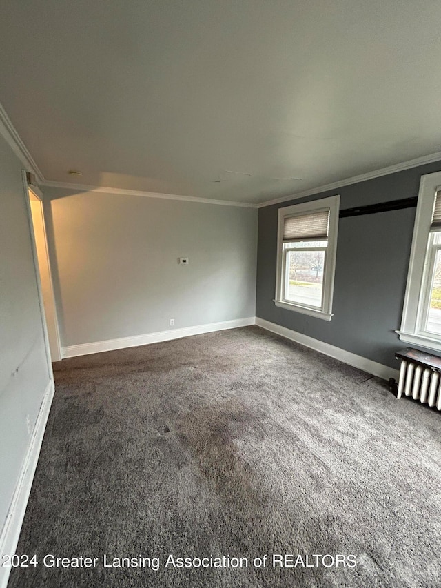 spare room featuring plenty of natural light, radiator heating unit, crown molding, and carpet flooring