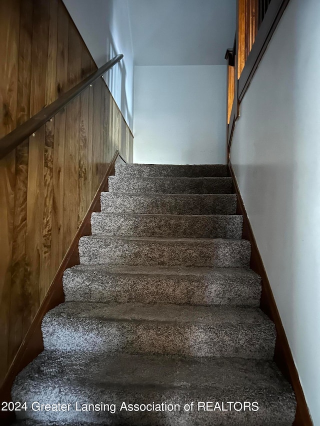 stairway featuring wooden walls