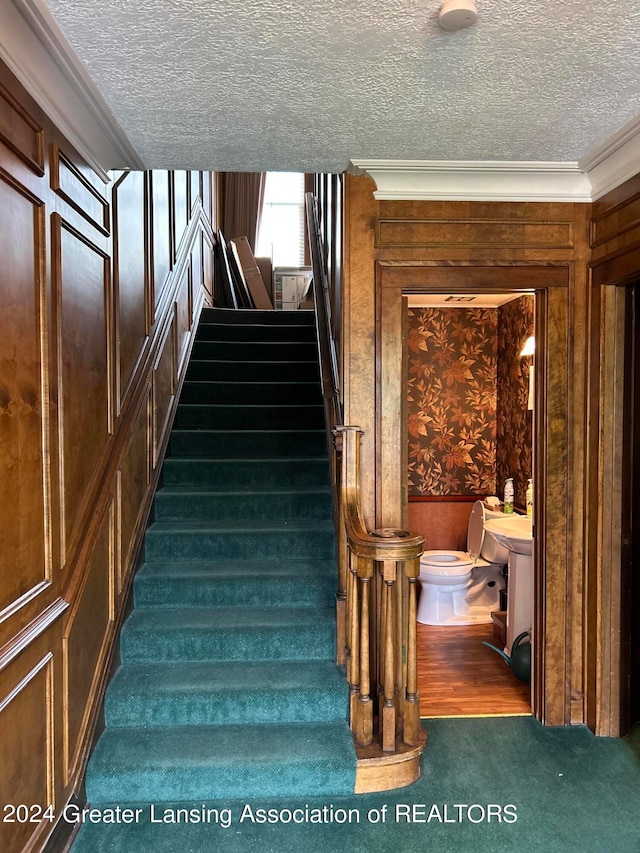 stairway with dark hardwood / wood-style flooring, a textured ceiling, and crown molding