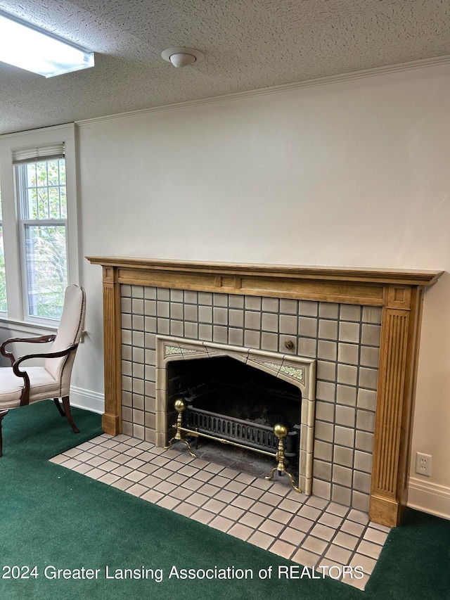 room details featuring a tiled fireplace, a textured ceiling, crown molding, and carpet flooring