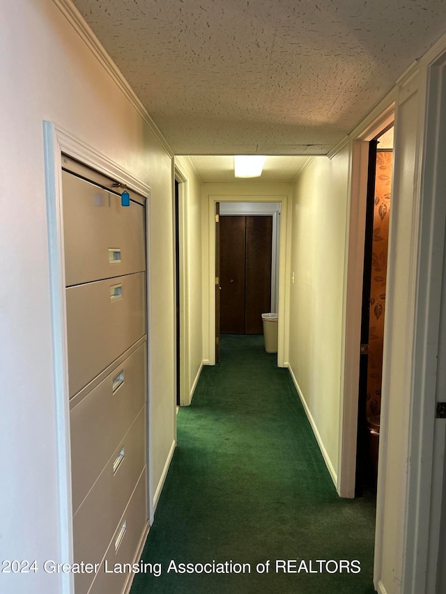 corridor featuring dark carpet and a textured ceiling