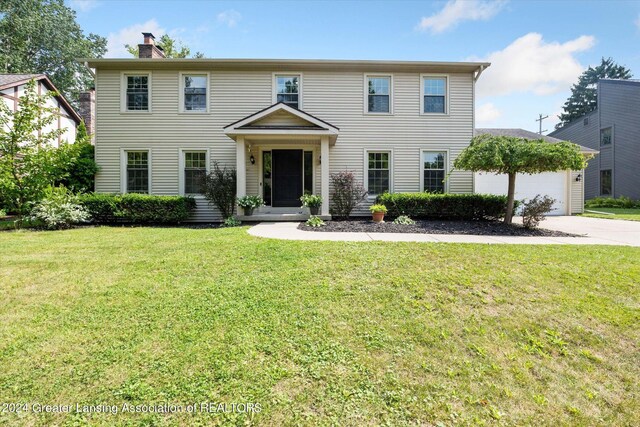 colonial inspired home with a garage and a front lawn