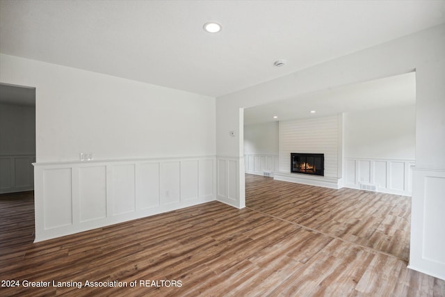 unfurnished living room featuring light hardwood / wood-style floors, a fireplace, and brick wall