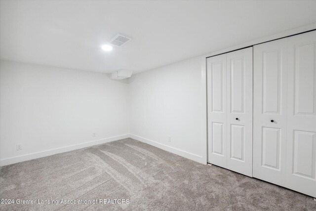 unfurnished bedroom with light colored carpet and a closet