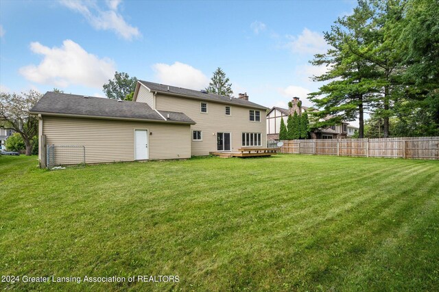 back of property with a deck and a lawn