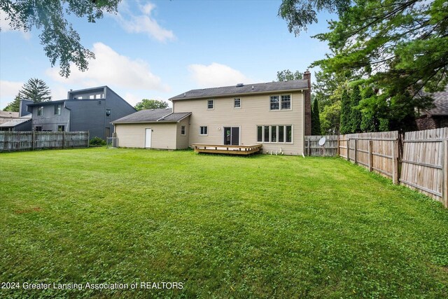 rear view of property featuring a deck and a lawn