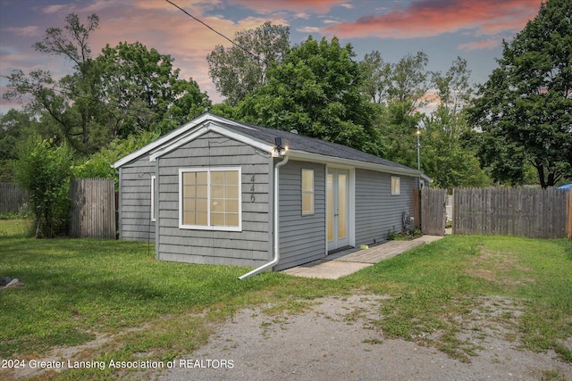 outdoor structure at dusk featuring a yard and a fenced backyard