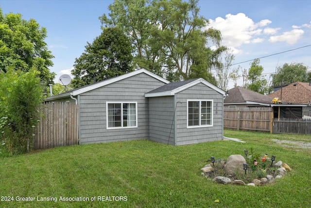 back of property featuring fence and a yard