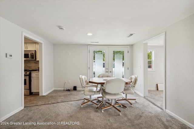 carpeted dining space with french doors, visible vents, and baseboards