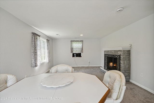 carpeted dining space with a lit fireplace, visible vents, and baseboards