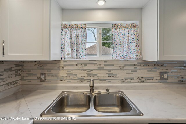 kitchen with white cabinetry, backsplash, and sink