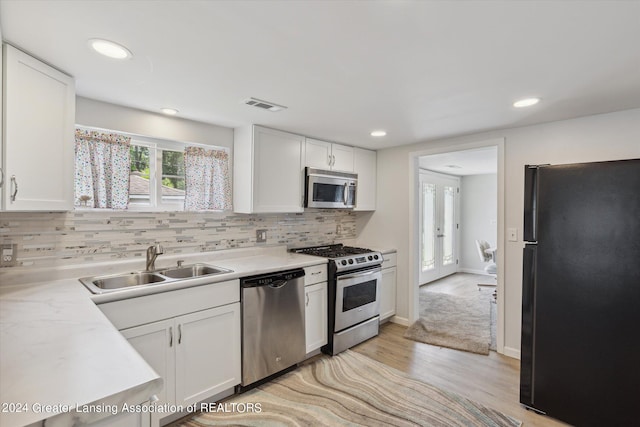 kitchen featuring white cabinetry, decorative backsplash, light wood-type flooring, sink, and appliances with stainless steel finishes