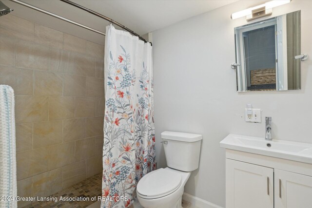 bathroom with curtained shower, toilet, and vanity