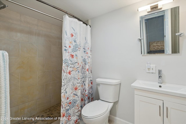 full bath featuring baseboards, a tile shower, vanity, and toilet