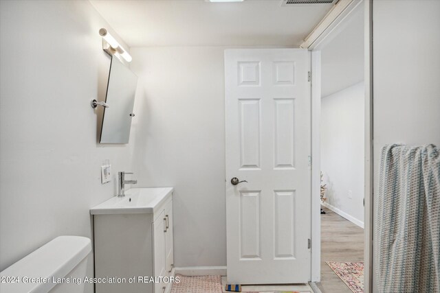 bathroom featuring vanity, wood-type flooring, and toilet