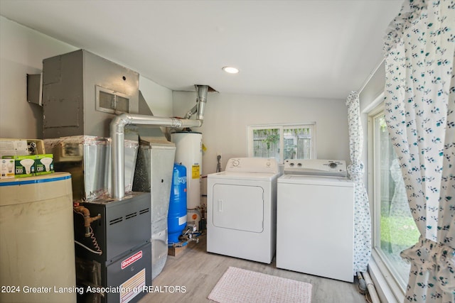 clothes washing area featuring light hardwood / wood-style floors, washer and clothes dryer, and gas water heater