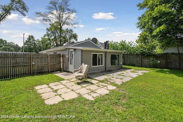 rear view of property featuring a patio area, a yard, and a fenced backyard