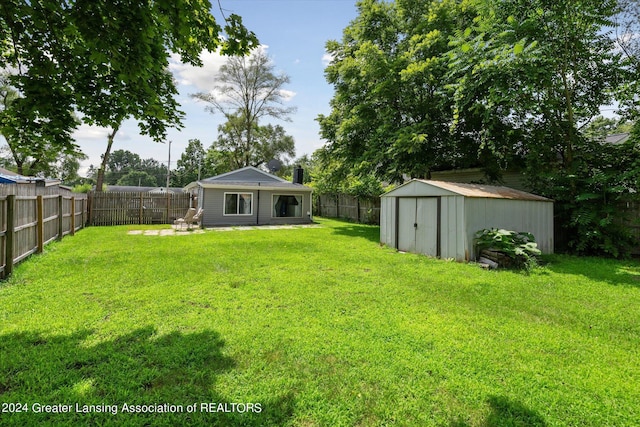 view of yard with a fenced backyard, a shed, and an outbuilding