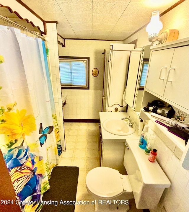 bathroom featuring vanity, toilet, tile walls, and walk in shower