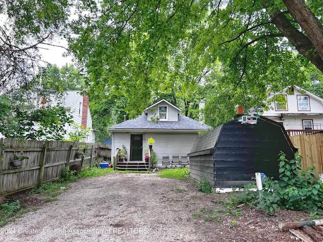 view of front facade featuring a fenced backyard, roof with shingles, and an outbuilding