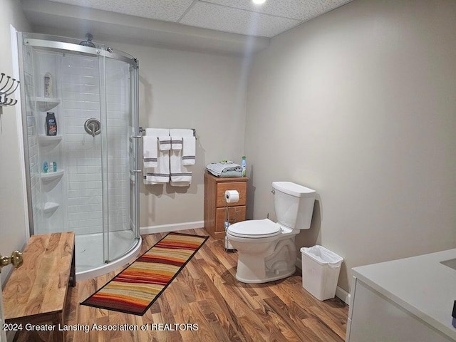 bathroom featuring a drop ceiling, toilet, walk in shower, and hardwood / wood-style floors