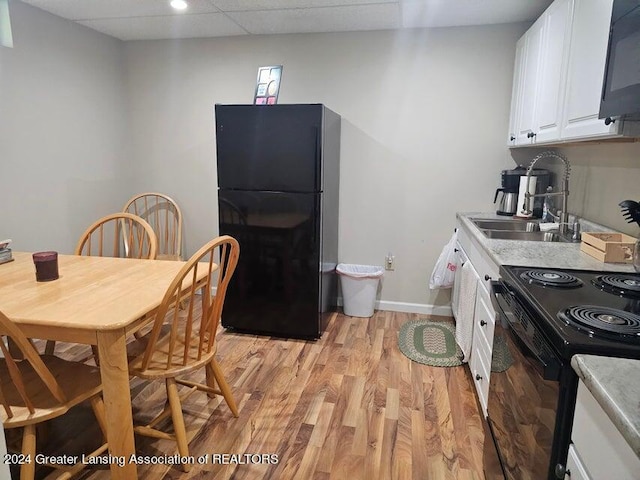 dining space featuring sink, a paneled ceiling, and light wood-type flooring