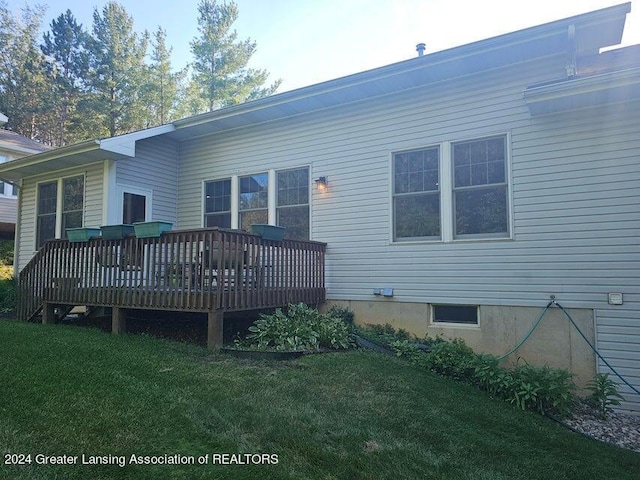 back of house featuring a wooden deck and a lawn