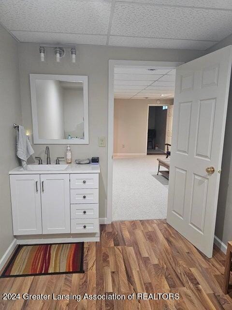 bathroom with wood-type flooring, vanity, and a paneled ceiling