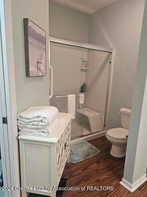 bathroom with toilet, hardwood / wood-style flooring, and an enclosed shower