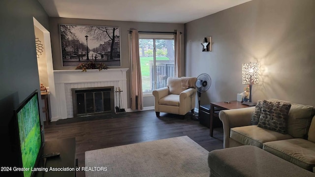 living room with a brick fireplace and dark hardwood / wood-style floors