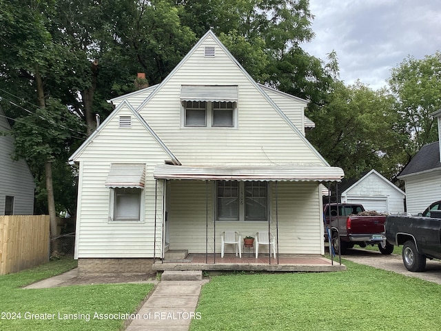 view of front of home with covered porch, a garage, and a front lawn