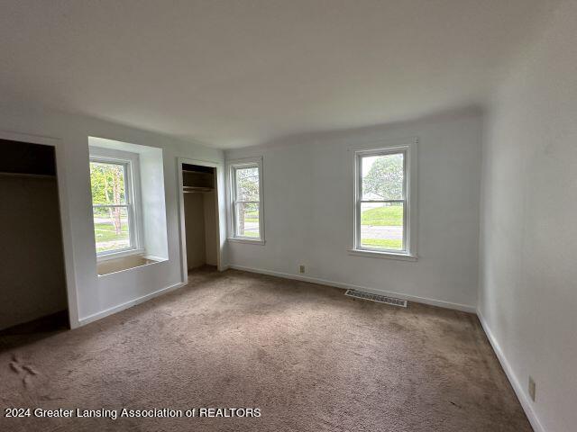 unfurnished bedroom with carpet, visible vents, and baseboards