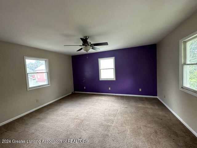 carpeted empty room with ceiling fan and baseboards