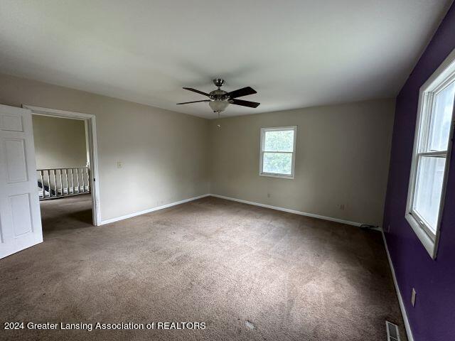 unfurnished bedroom featuring carpet floors, visible vents, baseboards, and a ceiling fan