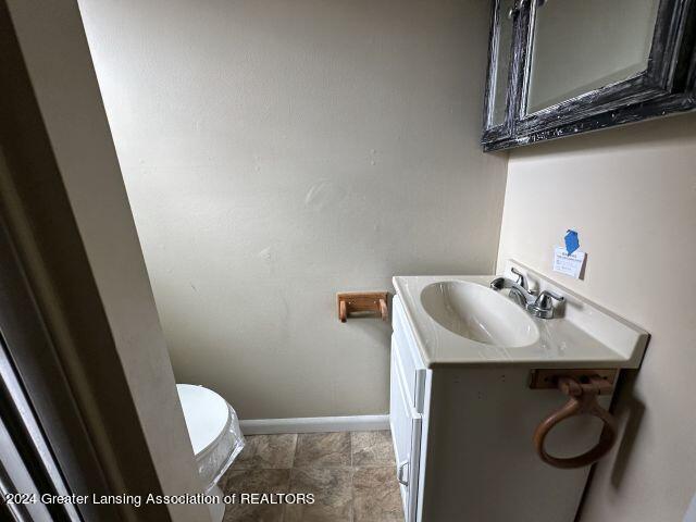 bathroom with toilet, vanity, and baseboards