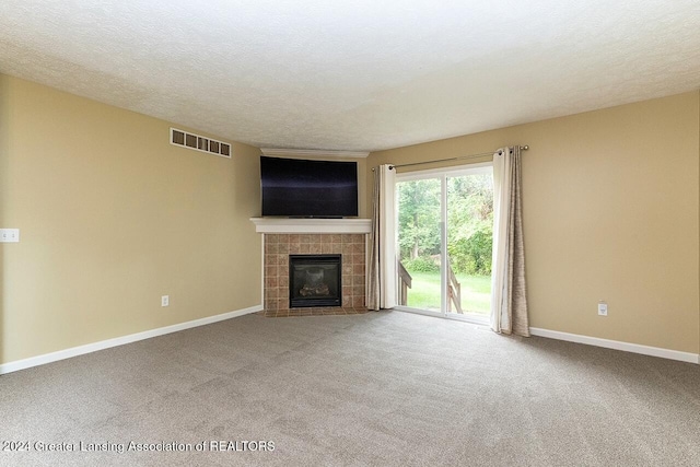 unfurnished living room with a textured ceiling, carpet, and a tile fireplace