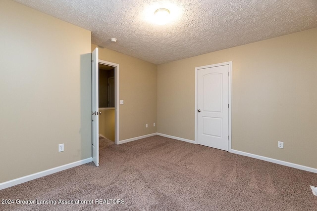 carpeted empty room with a textured ceiling