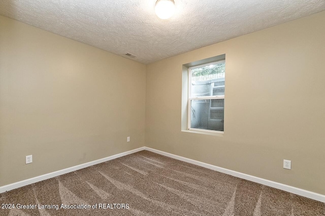 empty room with carpet and a textured ceiling